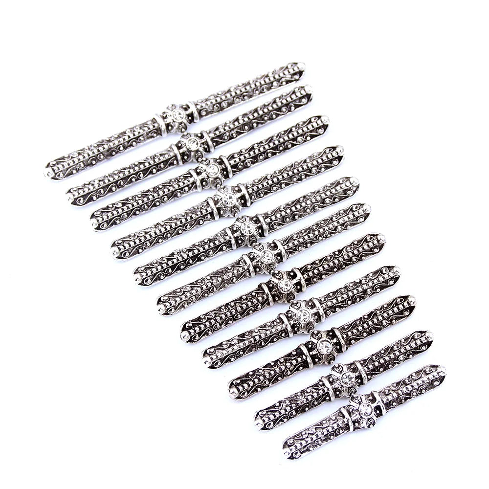 Set of ornate silver metal pen-shaped decorative rods arranged neatly on white background