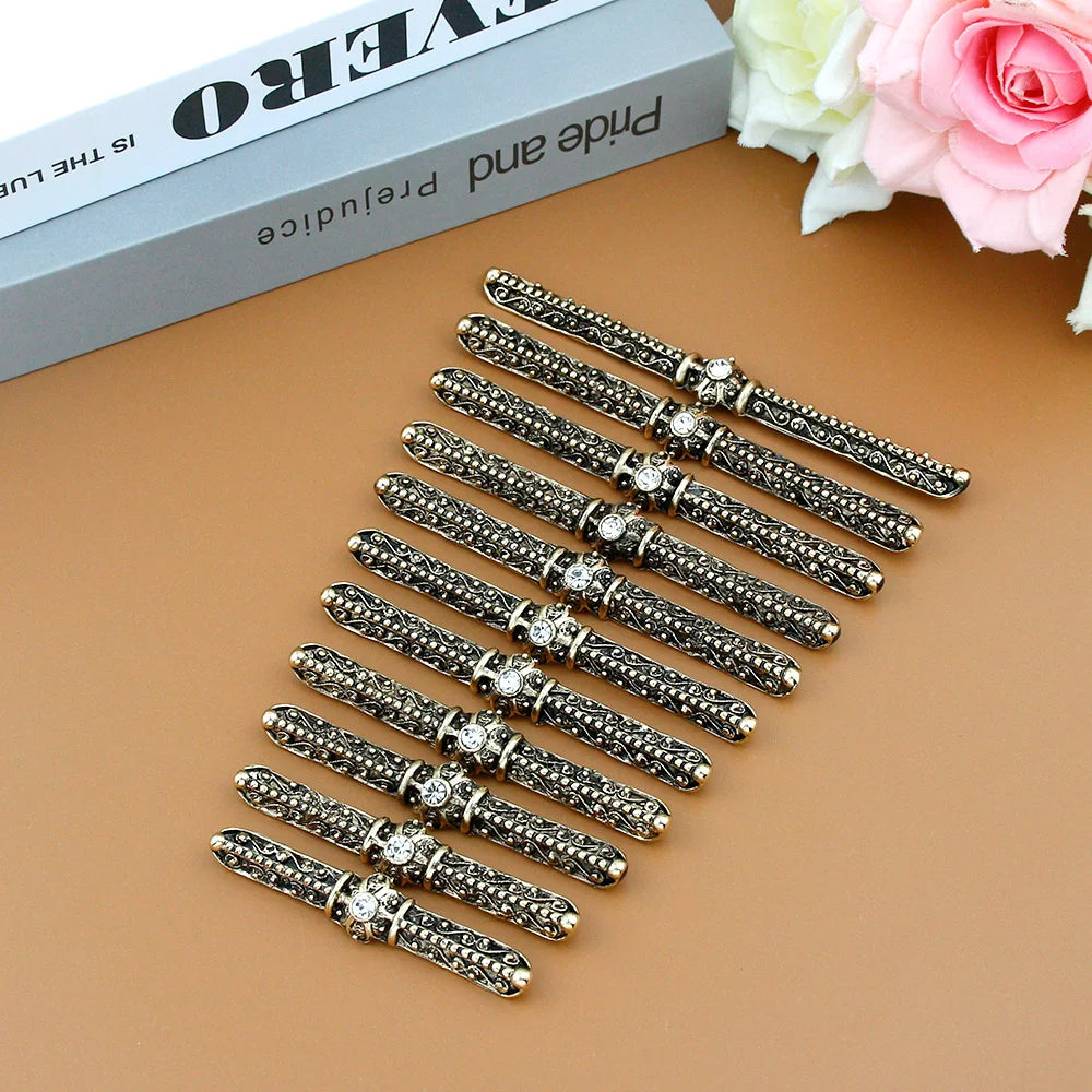 Set of ornate bronze hair clips with rhinestones on a brown surface, decorative accessories