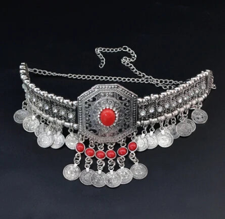 Vintage silver coin belt with red stones and intricate metalwork on a black background.