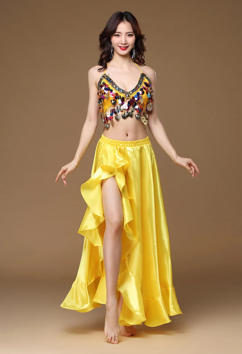 Woman modeling a yellow satin belly dance costume with coin details and ruffled skirt.