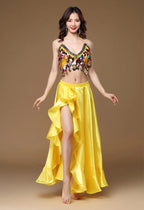 Woman modeling a yellow satin belly dance costume with coin details and ruffled skirt.