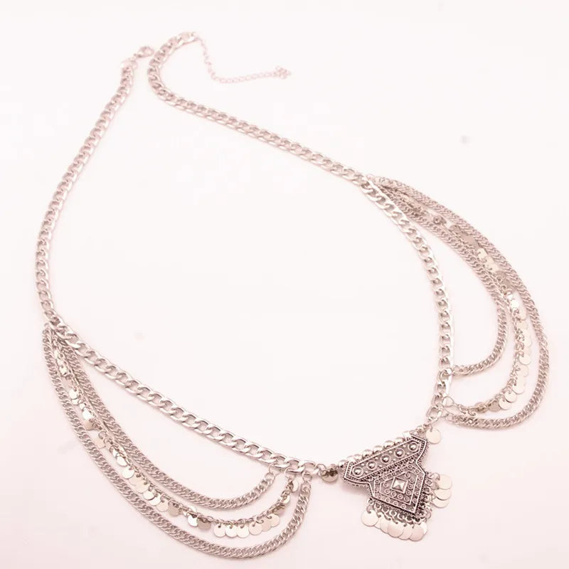 Layered silver chain necklace with geometric pendant and coin accents on white background