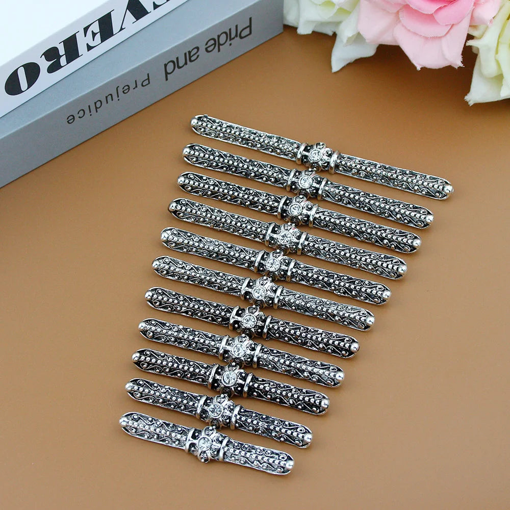 Set of ornate silver metal chopstick holders with floral patterns on a brown surface