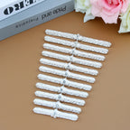 Set of twelve silver textured metal hair clips with rhinestone accents on brown surface
