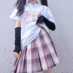 Girl in pastel plaid pleated skirt and cute graphic t-shirt, with black arm warmers