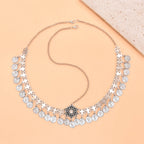 Silver coin statement necklace with floral centerpiece on a peach background