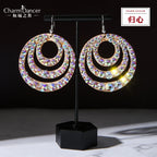Glittering circular rhinestone dangle earrings with layered hoops on display stand