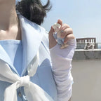 Person in light blue and white outfit holding small anime-style figure outdoors