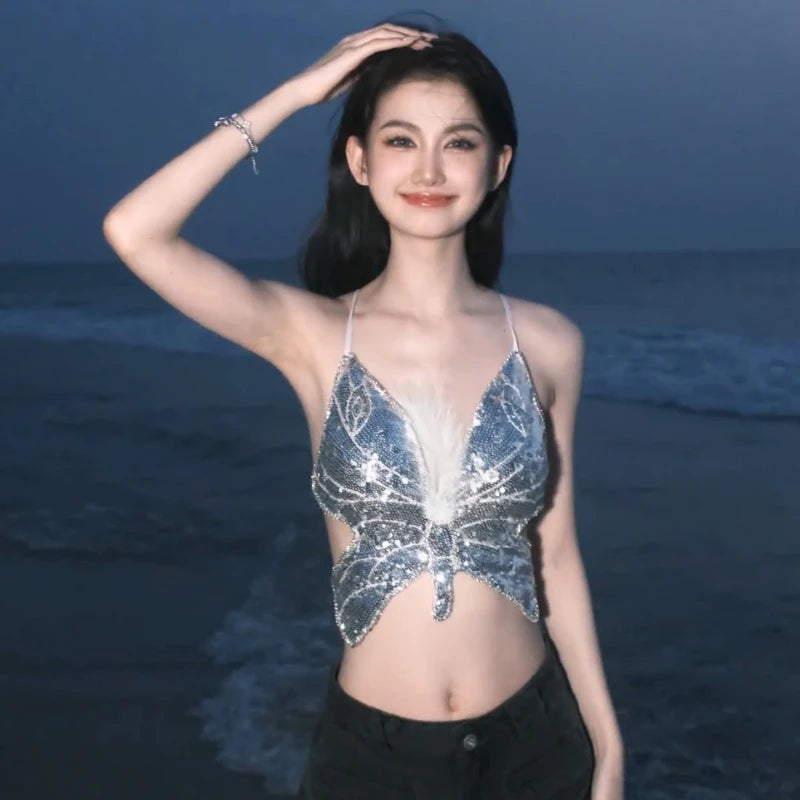Woman in a sequin butterfly crop top posing by the beach at dusk