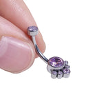 Hand holding a curved silver belly button ring with multiple purple gemstones