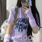 Woman in pastel purple graphic T-shirt and arm warmers with light backpack, taking mirror selfie