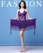Woman modeling a purple sequin belly dance costume with fringe against a blue background
