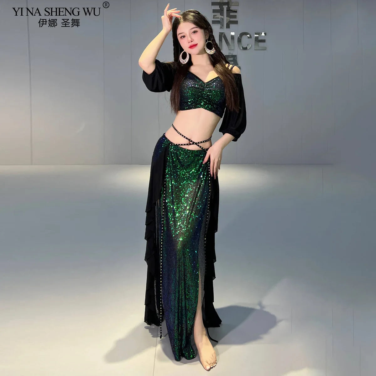 Woman in green sequin belly dance costume with black ruffled skirt, posing indoors
