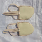 Pair of beige fabric foot pads with elastic straps on a textured surface