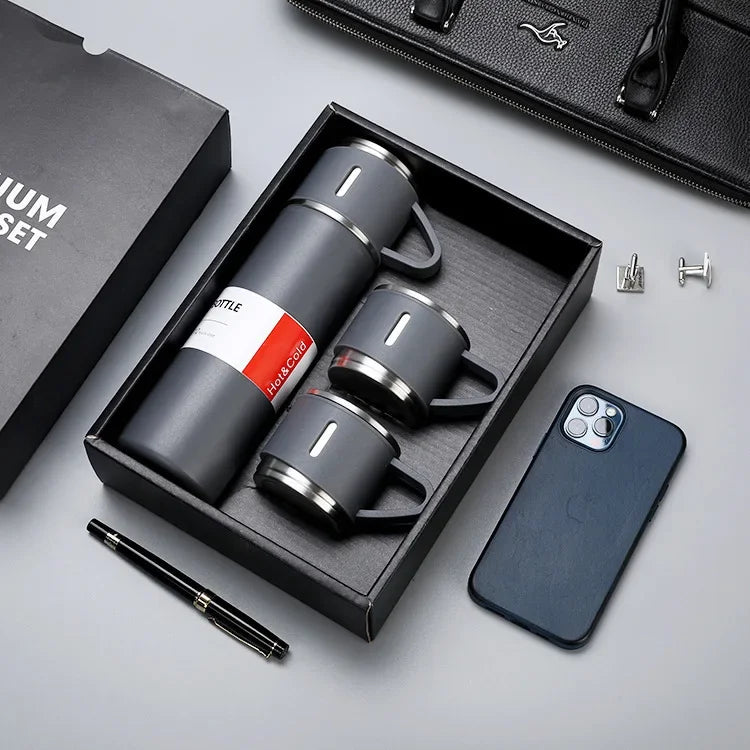 Matte black insulated thermos flask gift set with two matching mugs in a premium box, desk accessories nearby.