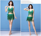 Woman modeling green sequin halter dance outfit with fringe skirt against blue background