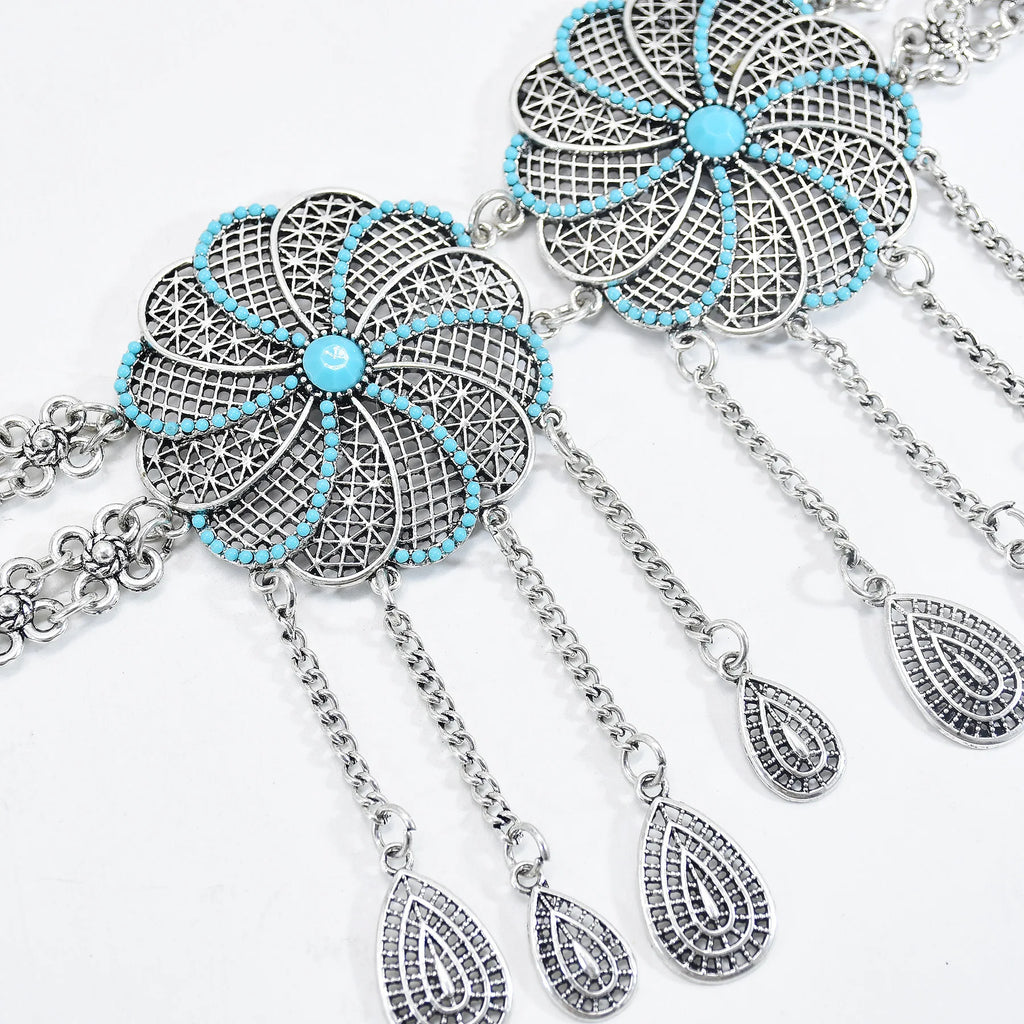 Silver filigree flower necklace with turquoise beads and dangling teardrop charms on white background.