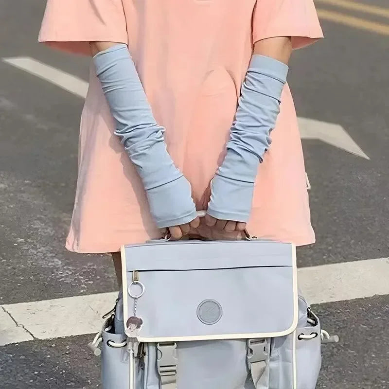 Person in pink shirt wearing light blue arm sleeves holding matching blue crossbody bag outdoors