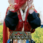 Person in traditional red and black Hanfu with ornate belt and gold jewelry outdoors