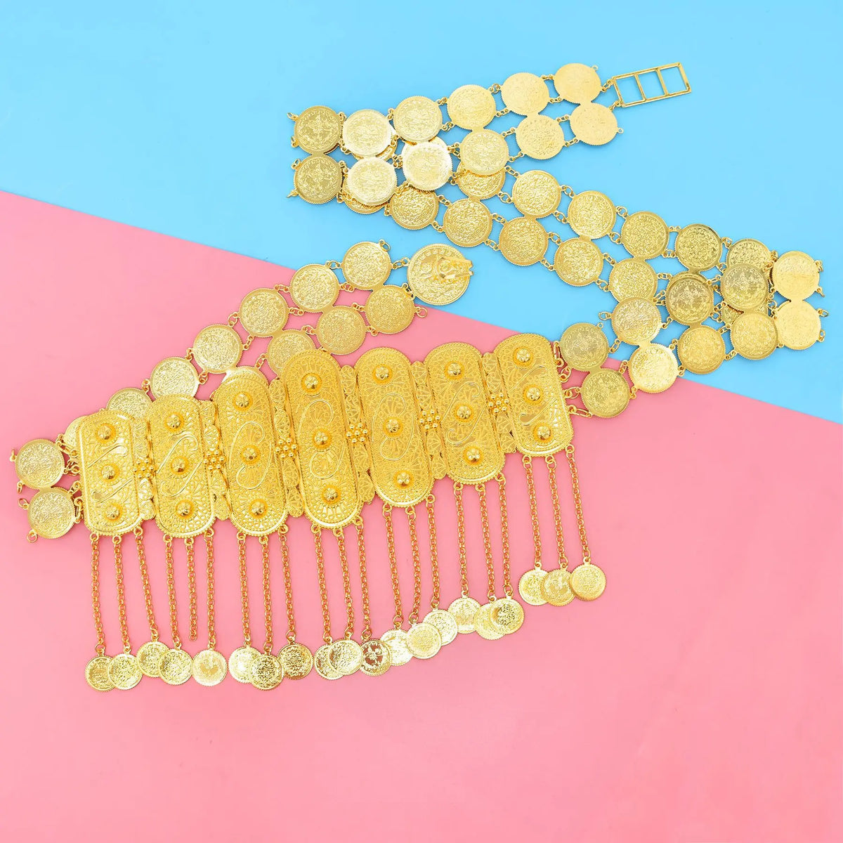 Gold coin belt with intricate engraved details and dangling coins on blue and pink background