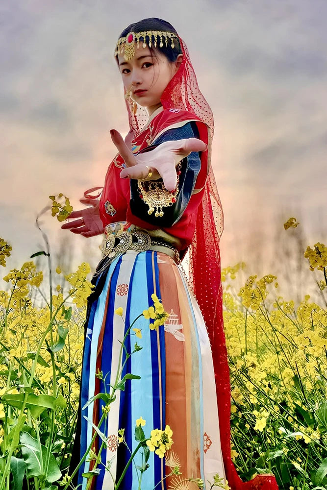 Woman in colorful traditional dress and headpiece posing in a yellow flower field at sunset