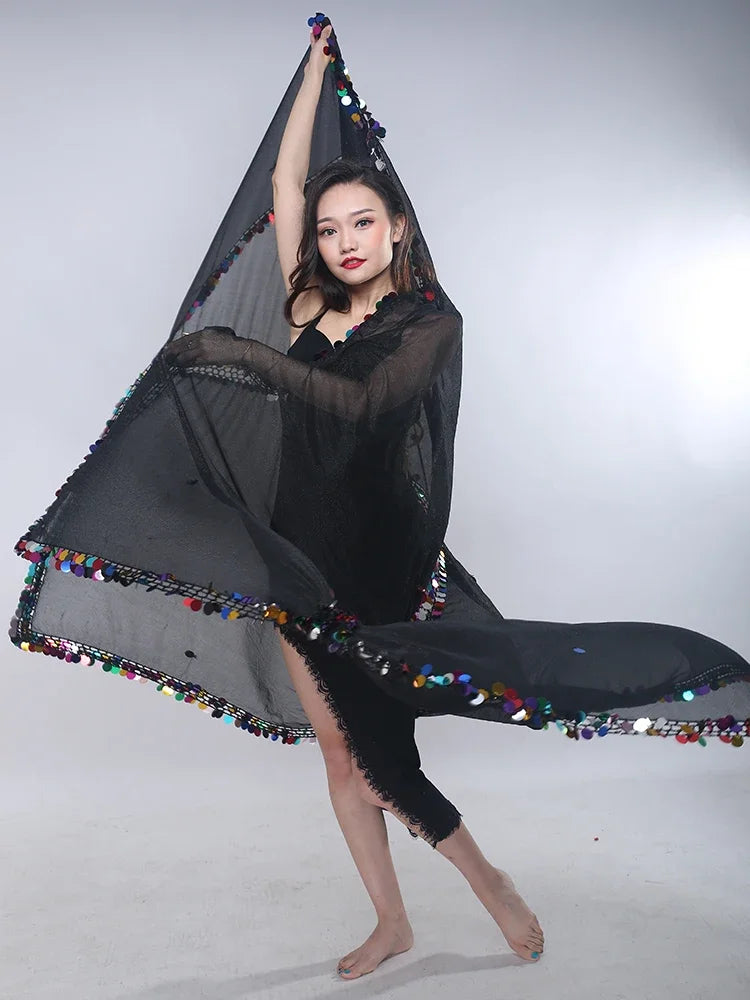 Woman dancing with sheer black scarf trimmed with colorful sequins in studio setting