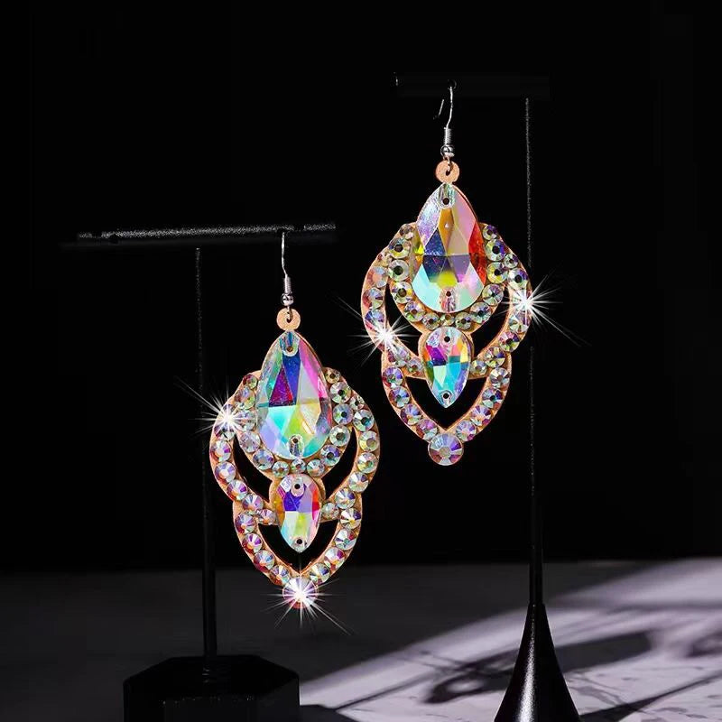 Iridescent crystal dangle earrings with teardrop shapes on black display stands