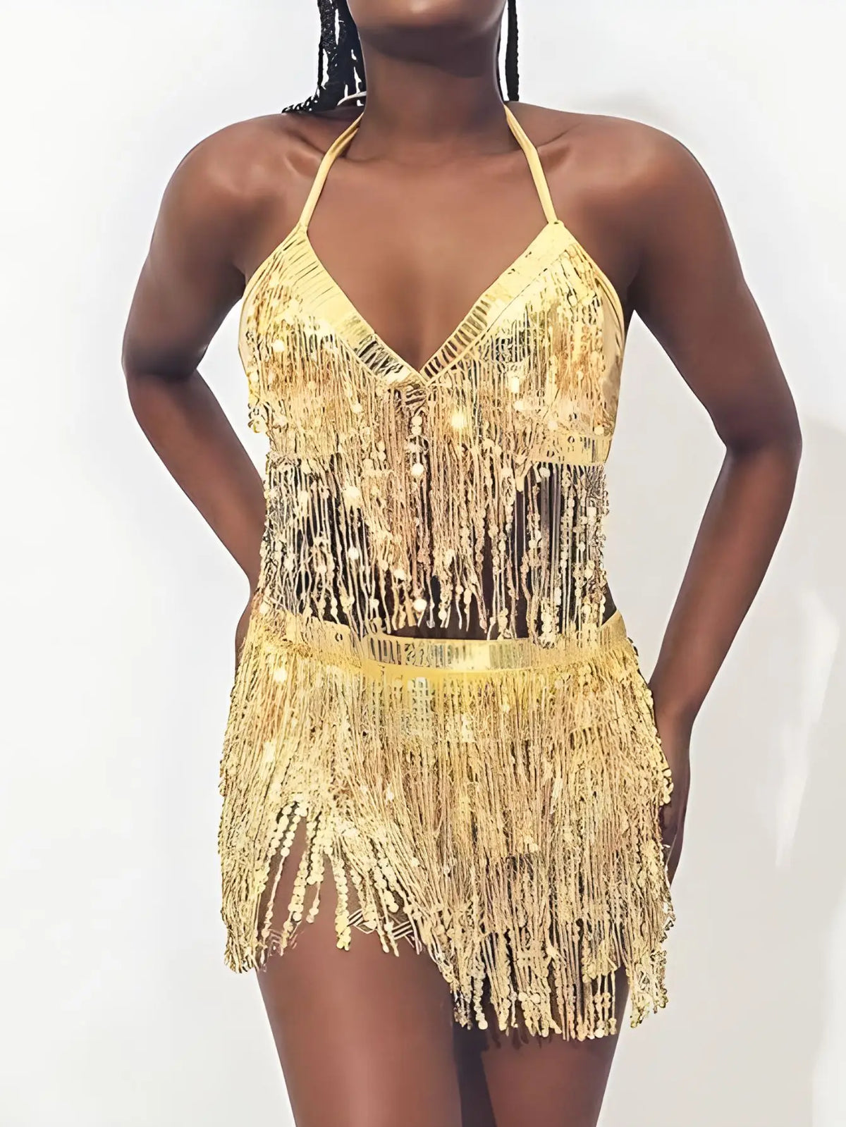 Woman wearing gold sequin fringe halter crop top and skirt set against white background