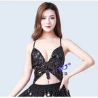 Woman wearing black sequin crop top with spaghetti straps and a cut-out front design
