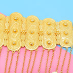 Ornate gold chain belt with intricate patterns and dangling chains on pink and blue background