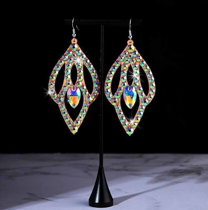 Colorful rhinestone dangle earrings with teardrop design on a display stand