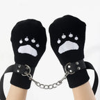 Black mittens with white paw prints, connected by a chain, worn on hands