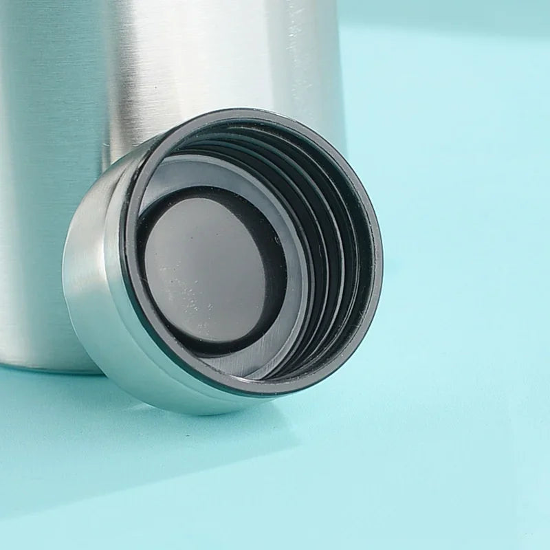 Stainless steel water bottle with black screw cap on blue background