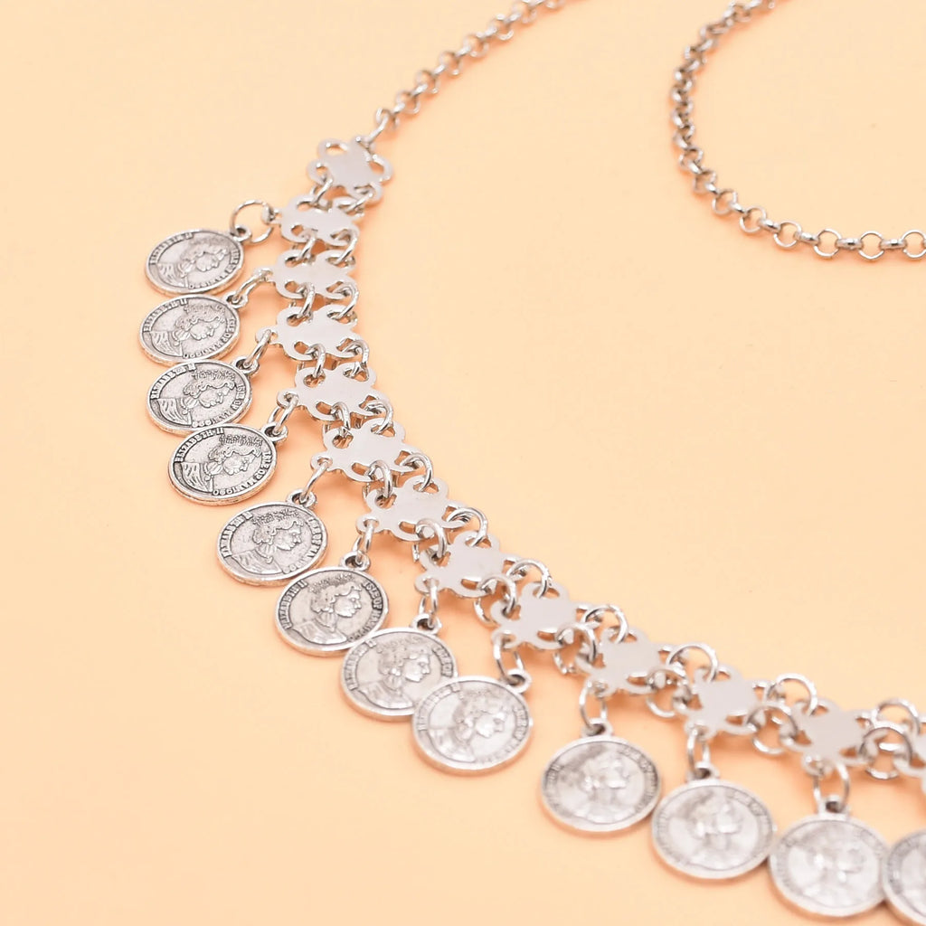 Silver coin charm necklace with multiple round pendants on a peach background
