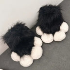 Fuzzy black and white paw-shaped slippers on a gray surface