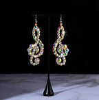 Rhinestone treble clef earrings with multicolor crystals on display stand, black background
