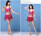 Woman modeling sparkly pink fringe two-piece dance costume against a blue background