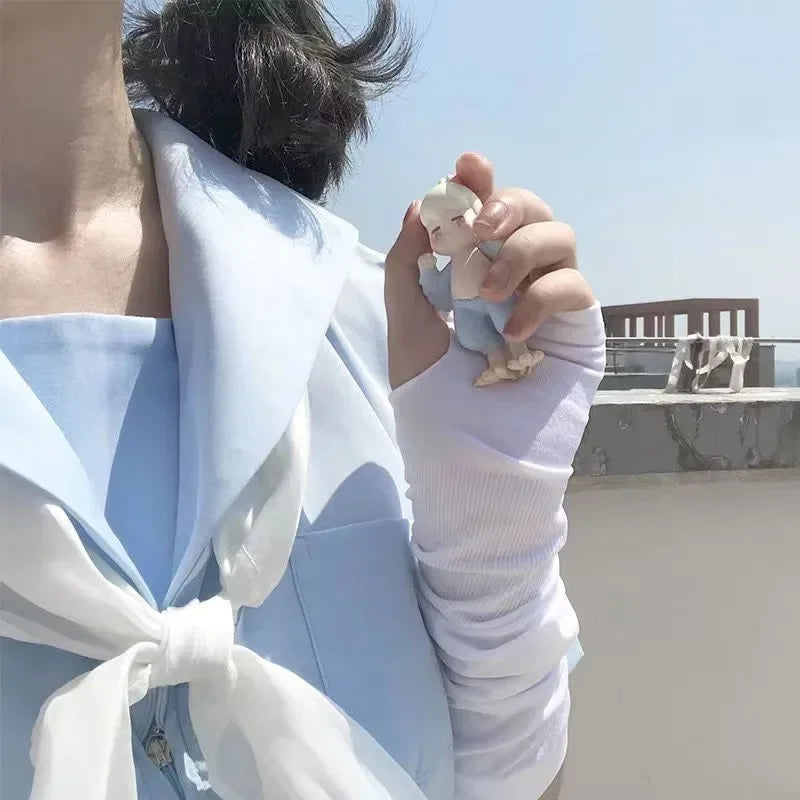 Person in pastel blue outfit holding small figurine outdoors on sunny day