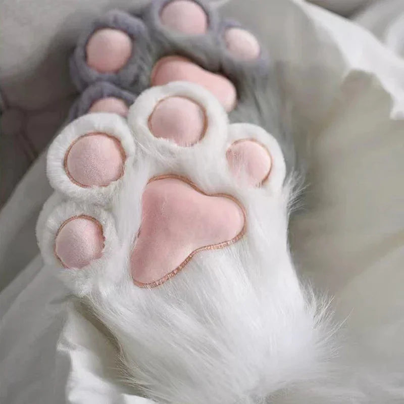 Plush cat paw slippers with pink toe pads on soft white bedding, cozy home accessory