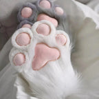 Plush cat paw slippers with pink toe pads on soft white bedding, cozy home accessory