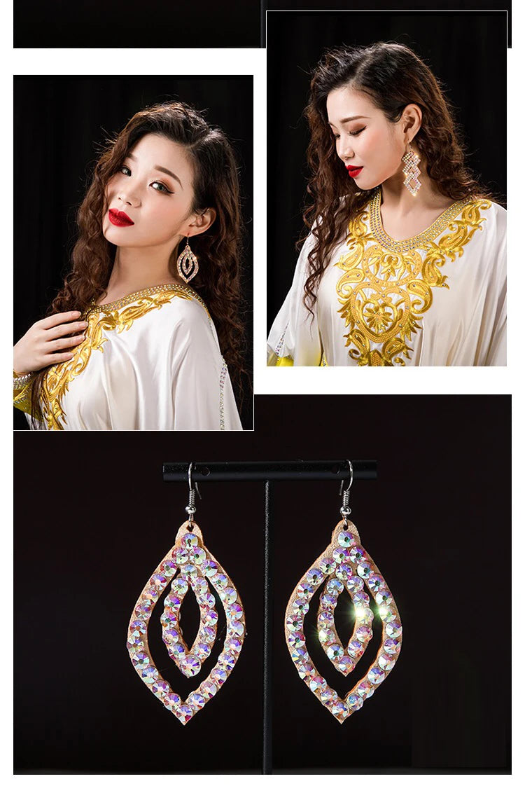 Woman wearing gold embroidered dress with large teardrop crystal dangle earrings, close-up