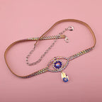 Rhinestone belt with jeweled evil eye design and teardrop pendant on pink background