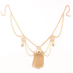 Gold layered statement necklace with decorative pendants and chain fringe on white background