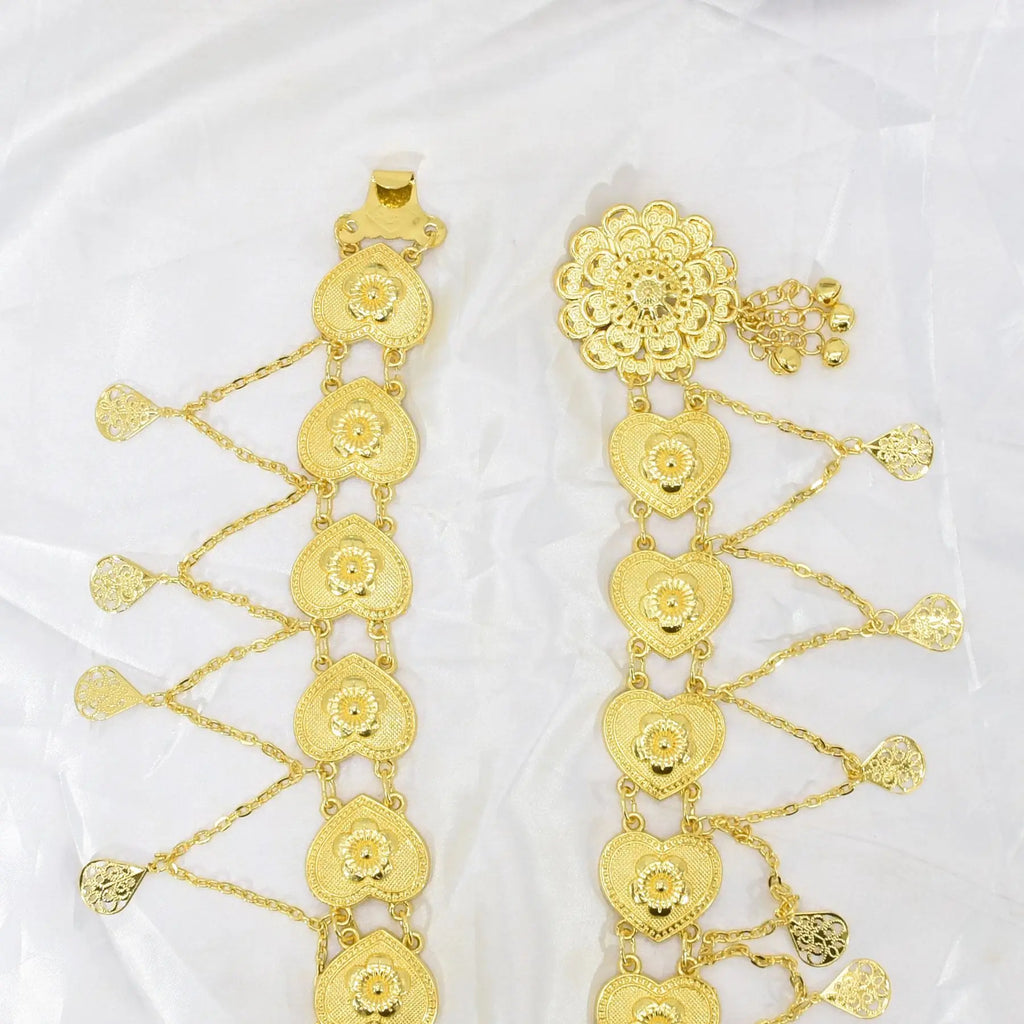 Gold-toned heart and floral pattern decorative chains on white fabric background