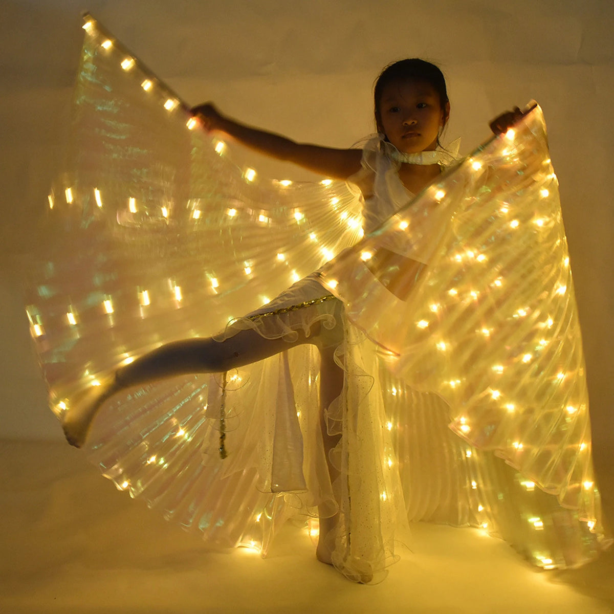 Child dancing in illuminated LED angel wings costume, glowing lights in soft golden tones