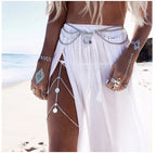 Woman on beach wearing boho jewelry, body chains, white sheer skirt, temporary metallic tattoos