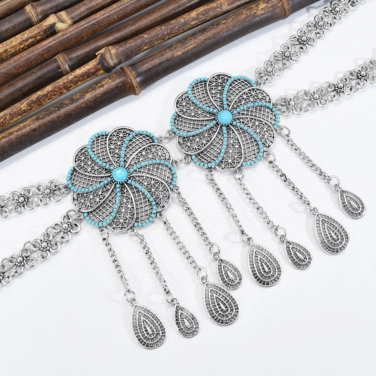 Boho silver necklace with turquoise accents and filigree floral pendants on white background