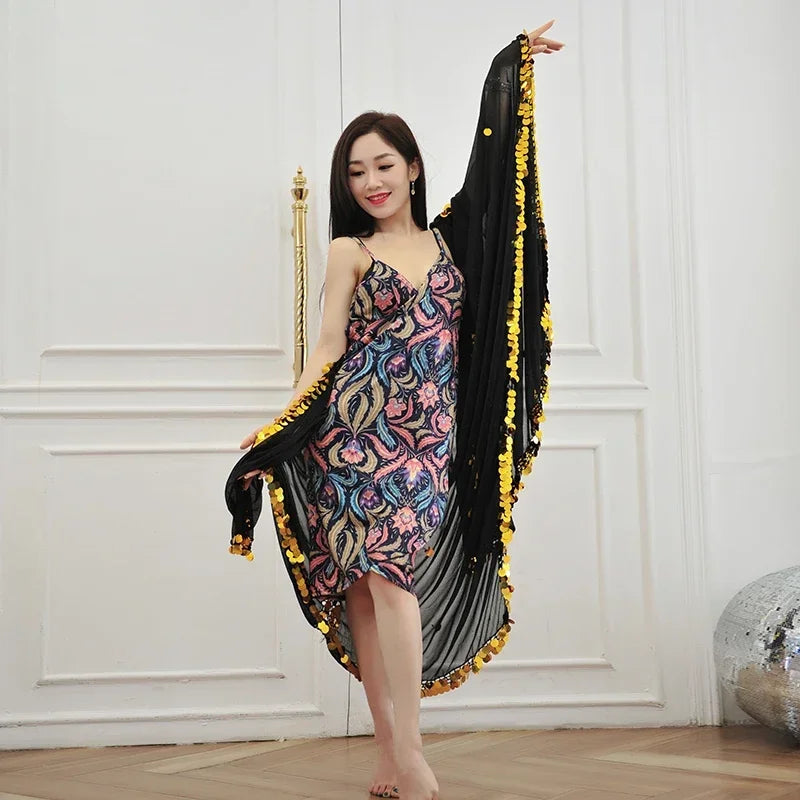 Woman in colorful patterned dress with black and gold shawl, posing indoors for fashion.