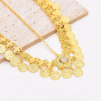 Gold coin necklace with crystal pendant, layered chain jewelry on beige stone background