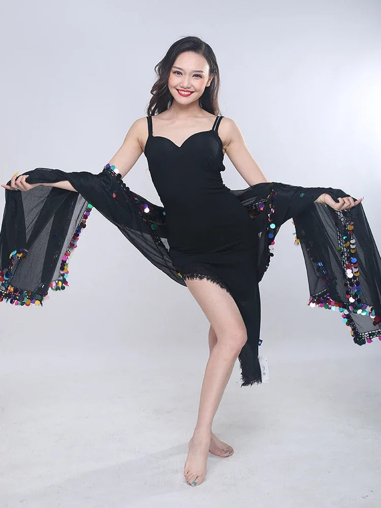 Woman in black sleeveless dress with sheer shawl decorated with colorful sequins posing indoors